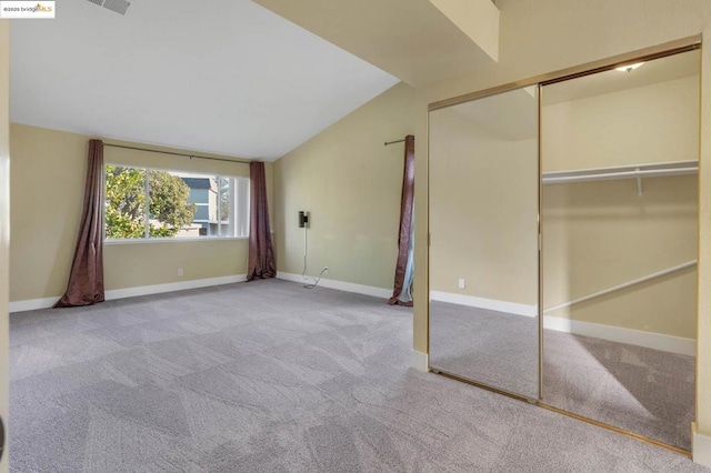 unfurnished bedroom featuring lofted ceiling, a closet, and light carpet