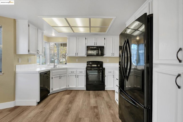 kitchen featuring white cabinets, light wood-type flooring, black appliances, and sink