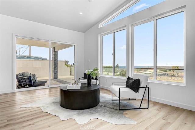 sitting room featuring light wood-type flooring and vaulted ceiling