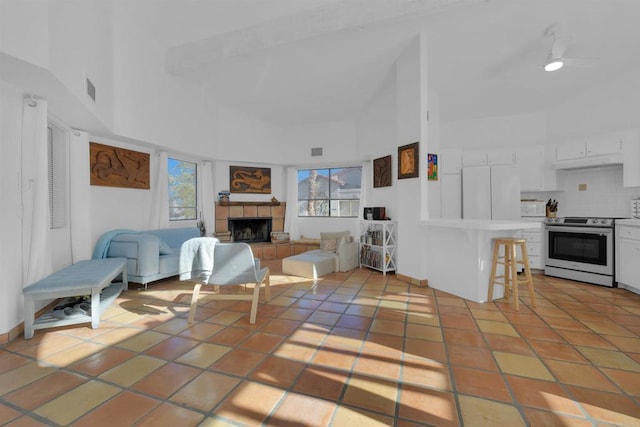 living room with a tile fireplace, a towering ceiling, and light tile patterned floors