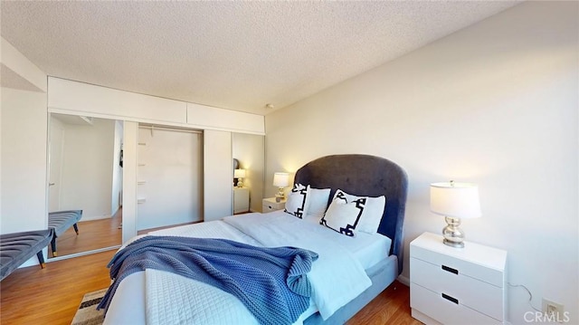 bedroom with hardwood / wood-style floors, a textured ceiling, and a closet