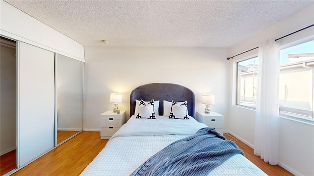 bedroom with light hardwood / wood-style floors, a closet, and a textured ceiling