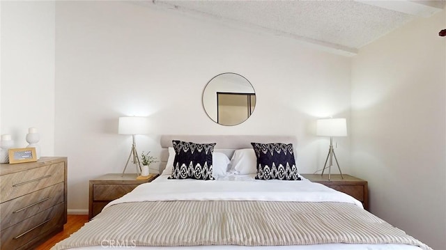 bedroom featuring lofted ceiling, wood-type flooring, and a textured ceiling