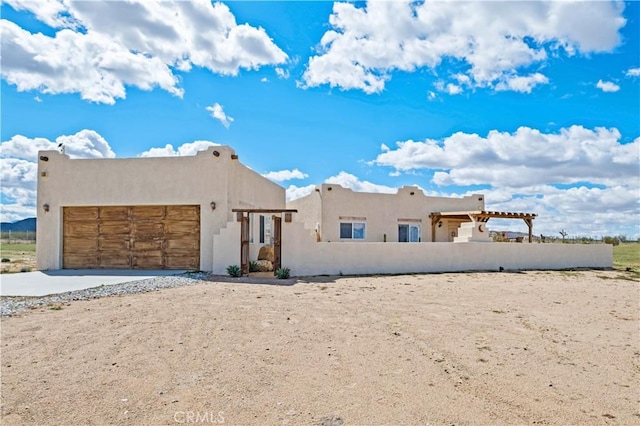 1388 Fortuna Ave, Landers, CA 92285 - pueblo-style house with an attached garage, stucco siding, and driveway