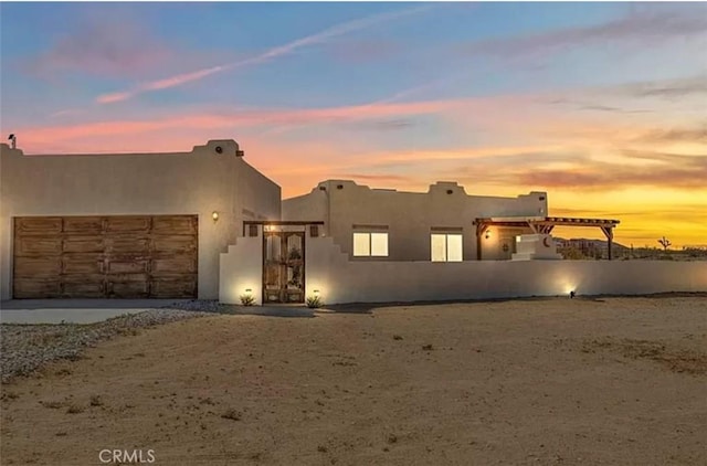 pueblo-style house featuring an attached garage and stucco siding