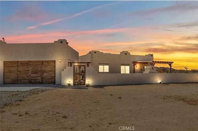 1388 Fortuna Ave, Landers, CA 92285 - southwest-style home featuring an attached garage, dirt driveway, and stucco siding