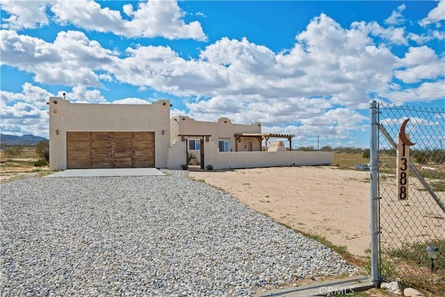 1388 Fortuna Ave, Landers, CA 92285 - southwest-style home with a garage, stucco siding, and gravel driveway
