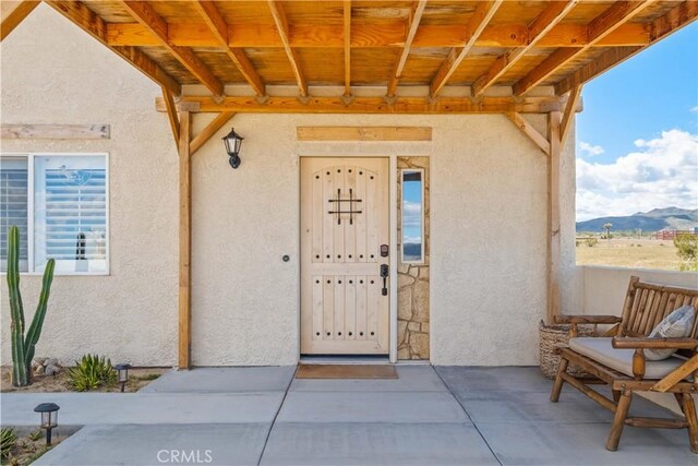 view of exterior entry featuring a patio and a mountain view