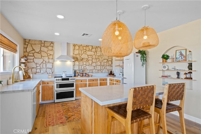 1388 Fortuna Ave, Landers, CA 92285 - kitchen with double oven range, wall chimney range hood, freestanding refrigerator, and light wood-type flooring