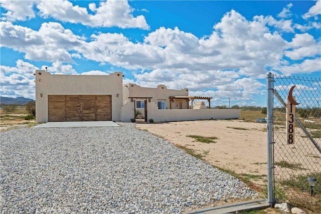 1388 Fortuna Ave, Landers, CA 92285 - pueblo-style house featuring a garage, stucco siding, and gravel driveway