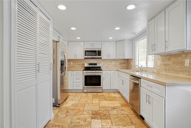 kitchen featuring sink, stainless steel appliances, backsplash, and white cabinetry