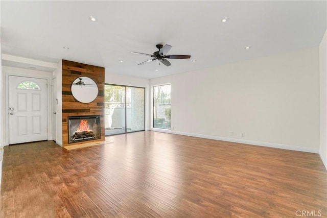 unfurnished living room featuring a large fireplace, ceiling fan, and light wood-type flooring