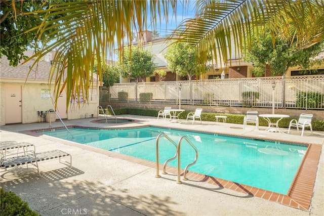 view of swimming pool featuring a hot tub and a patio