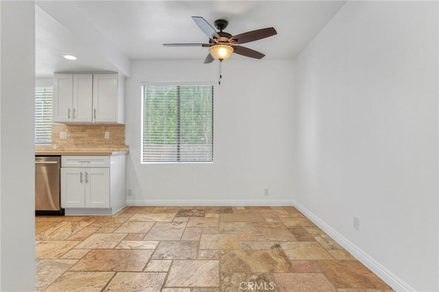 interior space with backsplash, white cabinetry, a wealth of natural light, and dishwasher