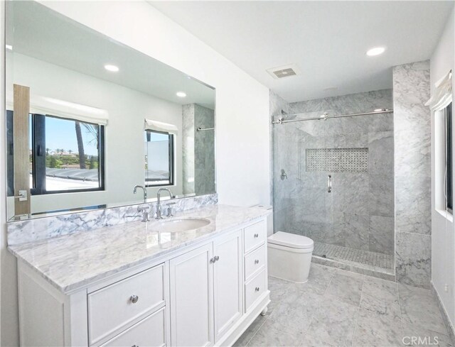 bathroom featuring toilet, a tile shower, and vanity