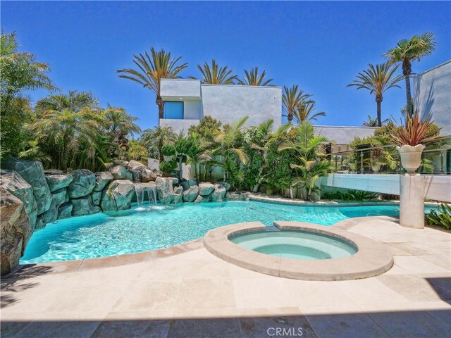 view of swimming pool with pool water feature and an in ground hot tub