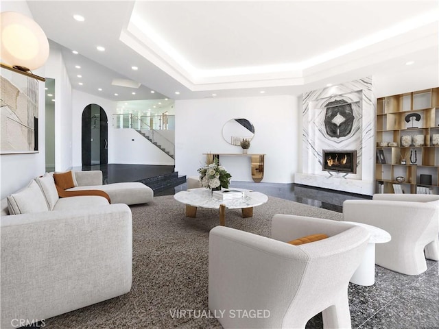 living room with a premium fireplace, built in shelves, and a tray ceiling