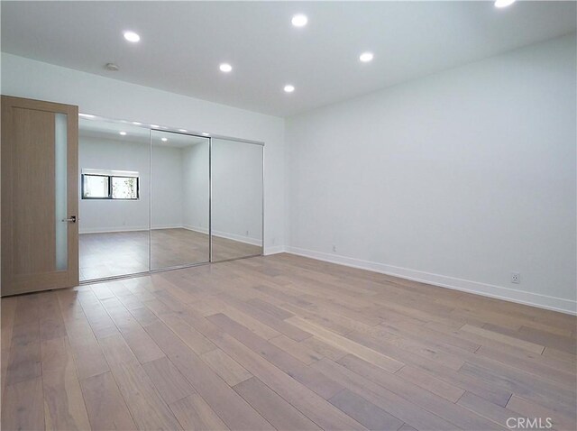 unfurnished bedroom featuring light wood-type flooring and a closet