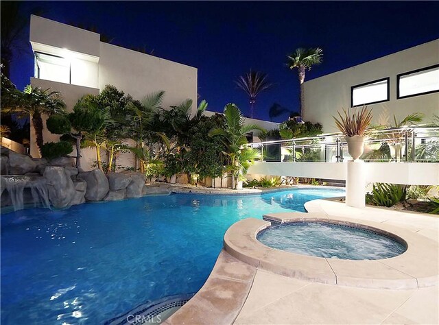 pool at twilight with an in ground hot tub