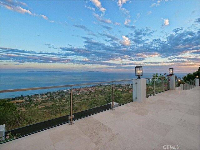 patio terrace at dusk with a balcony and a water view