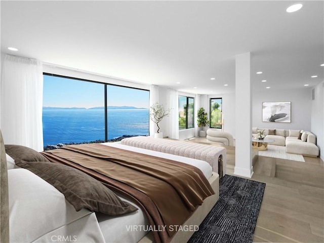 bedroom with light hardwood / wood-style flooring and a water view