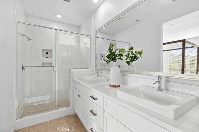 full bathroom featuring double vanity, a shower stall, a sink, and tile patterned floors