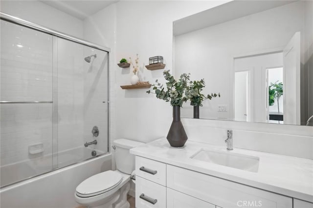 bathroom with shower / bath combination with glass door, vanity, and toilet