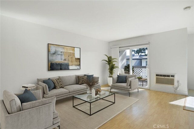 living room featuring light wood-type flooring and a wall unit AC