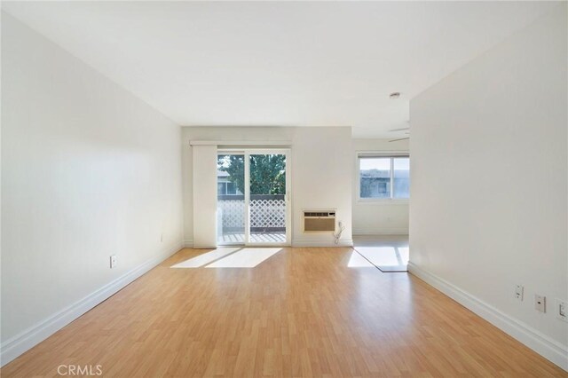 spare room with an AC wall unit, ceiling fan, and light hardwood / wood-style flooring