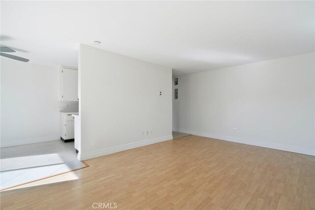 empty room with ceiling fan and light hardwood / wood-style flooring