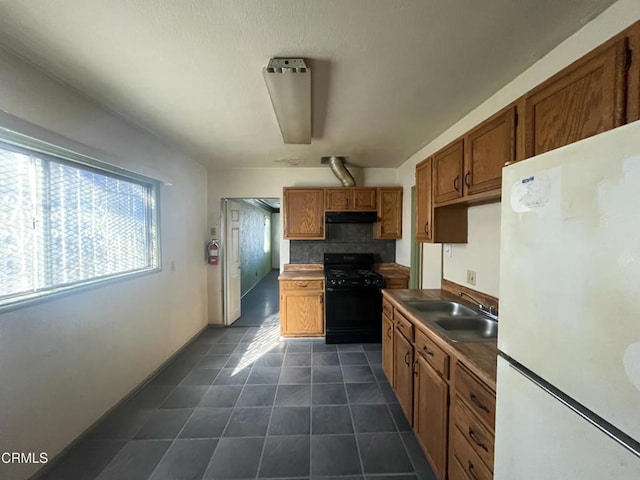 kitchen featuring sink, white fridge, and black gas range oven