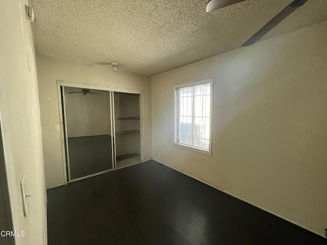 unfurnished bedroom with a textured ceiling, a closet, and hardwood / wood-style floors