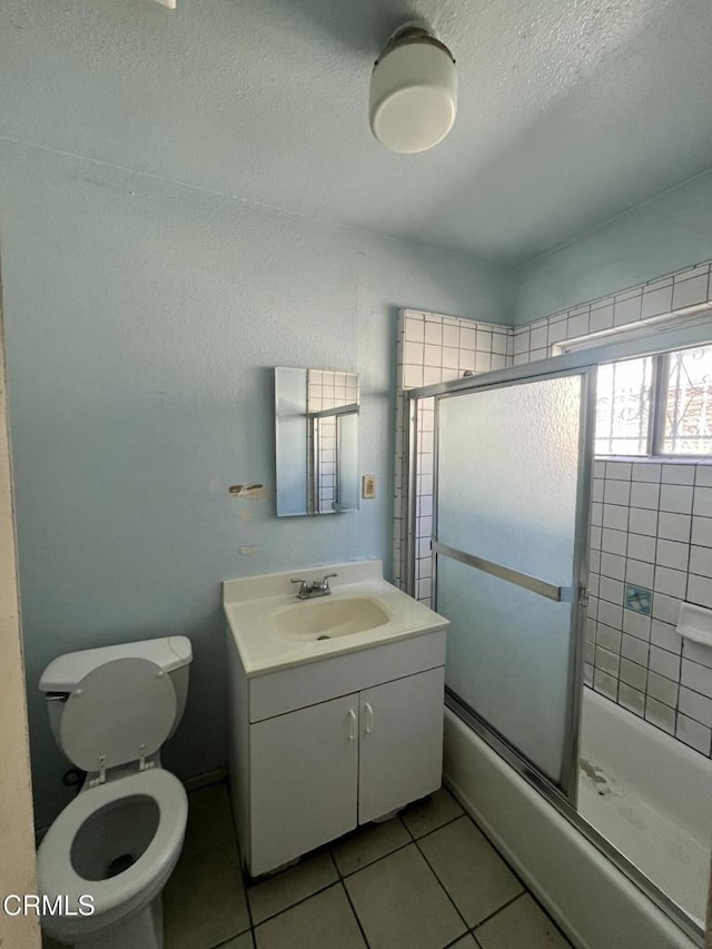 full bathroom featuring toilet, vanity, tile patterned flooring, and shower / bath combination with glass door