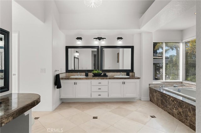 bathroom with a relaxing tiled tub, tile patterned flooring, and vanity