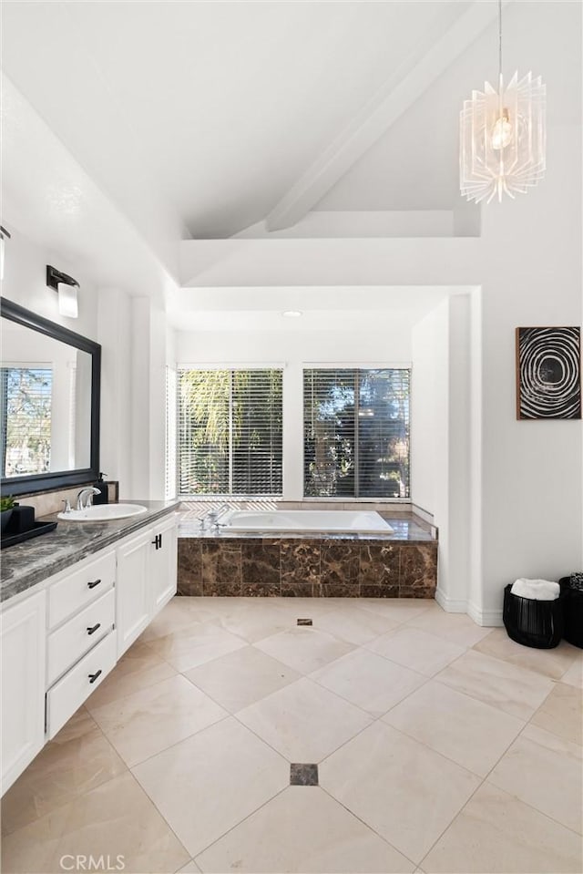 bathroom with a chandelier, vanity, tiled tub, and beamed ceiling