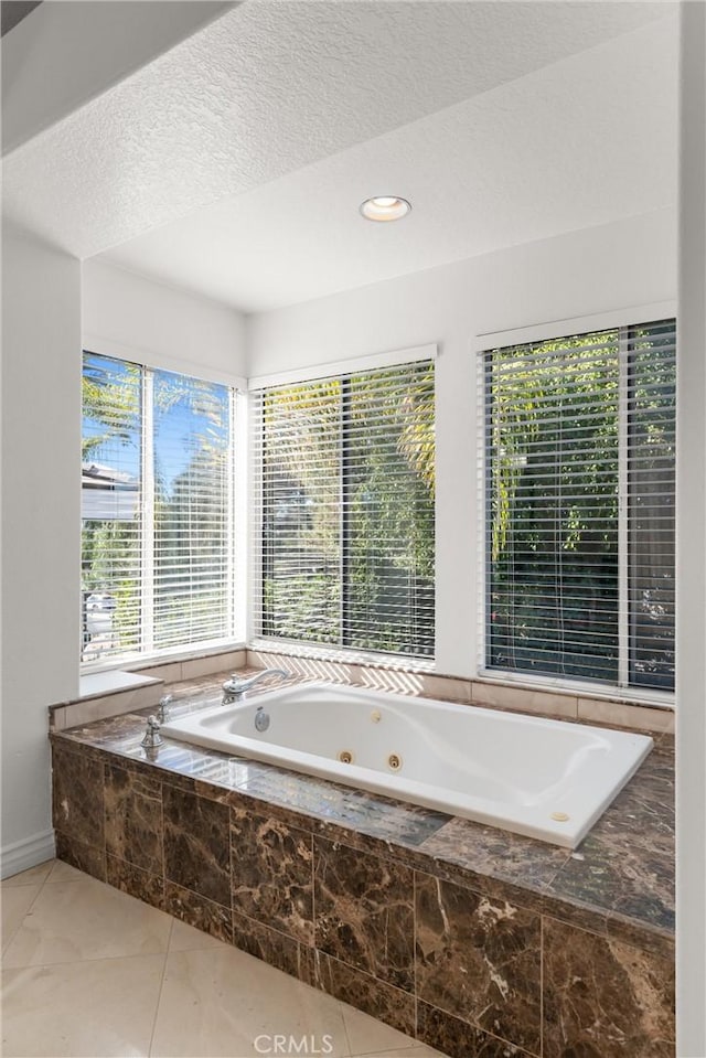 bathroom with a textured ceiling and tiled bath