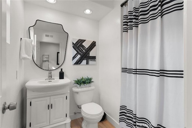 bathroom with toilet, wood-type flooring, and vanity