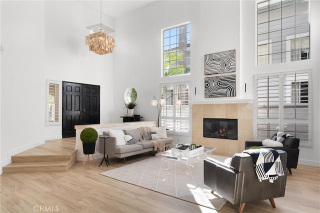 living room with a high ceiling, a tile fireplace, hardwood / wood-style floors, and plenty of natural light