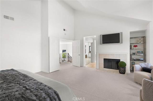 carpeted bedroom featuring high vaulted ceiling and a tiled fireplace