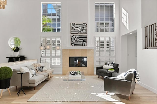 interior space with a high ceiling, a tiled fireplace, and hardwood / wood-style floors