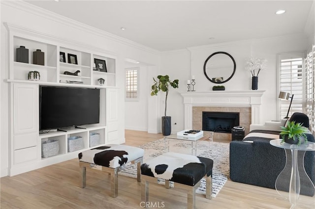 living room with light wood-type flooring, a tiled fireplace, and a healthy amount of sunlight