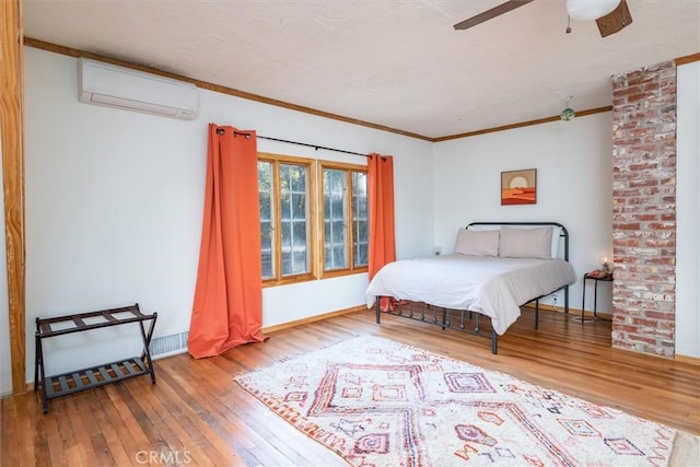 bedroom featuring ornamental molding, a wall mounted AC, ceiling fan, and wood-type flooring