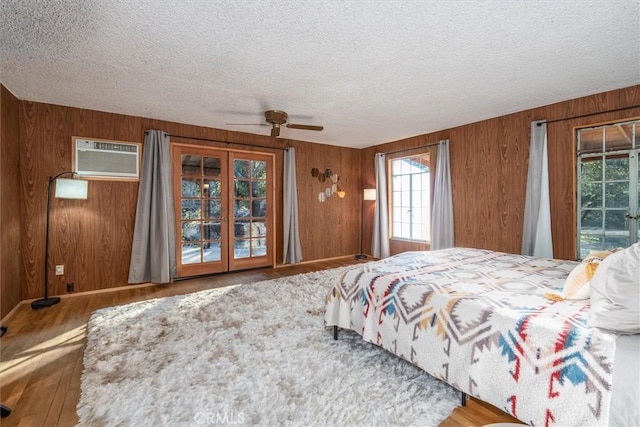 bedroom with a textured ceiling, wood walls, ceiling fan, and access to exterior