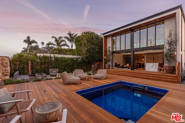 pool at dusk with a deck and outdoor lounge area