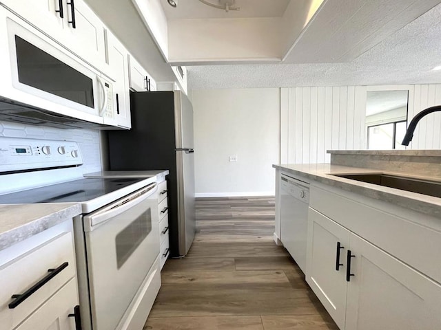 kitchen featuring sink, white cabinetry, a textured ceiling, white appliances, and dark hardwood / wood-style floors