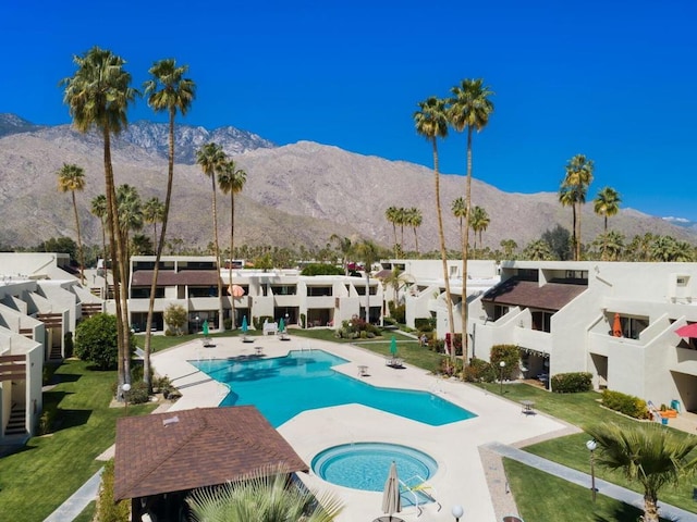 view of swimming pool with a community hot tub, a yard, a patio, and a mountain view