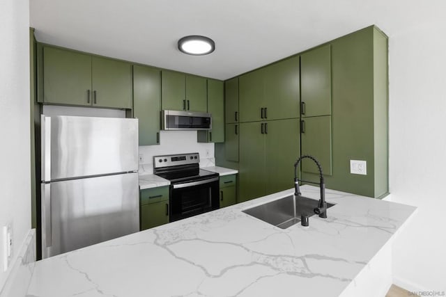 kitchen featuring light stone counters, stainless steel appliances, sink, and green cabinets