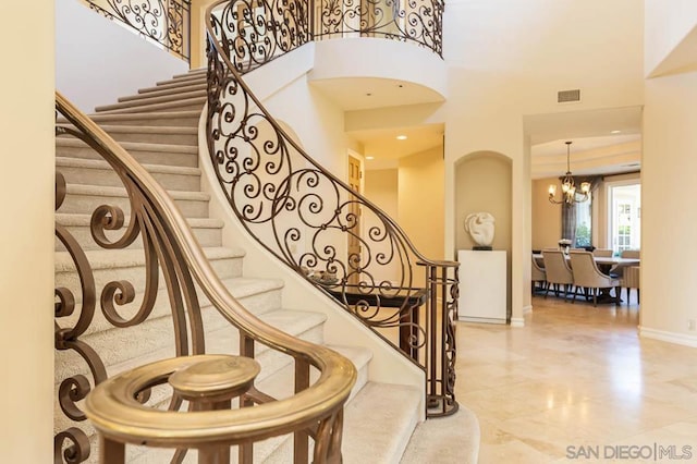 staircase with a high ceiling and a notable chandelier