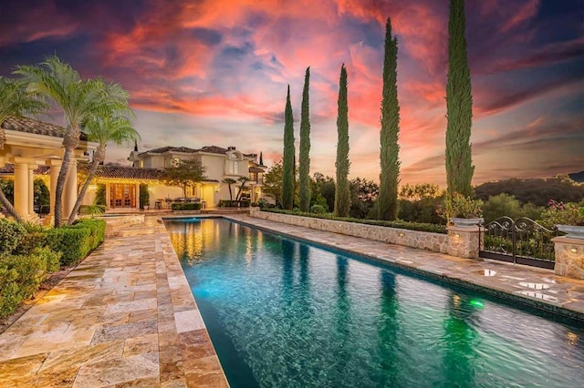 pool at dusk with a patio area