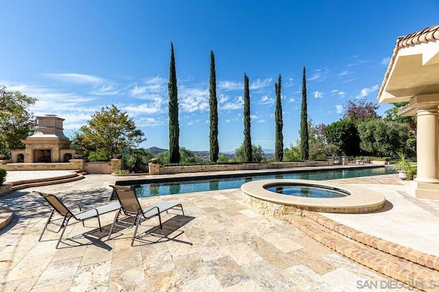 view of swimming pool featuring an in ground hot tub, an outdoor fireplace, and a patio area